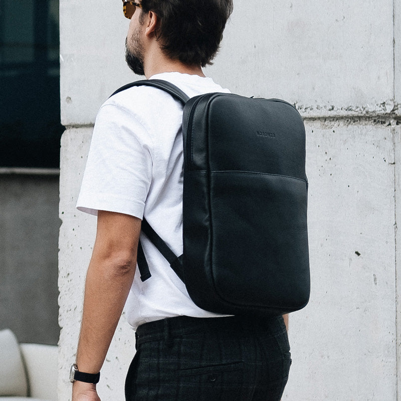 Homem usando a Mochila Slim Workplace NW108 da Nordweg em couro legítimo preto, com design minimalista e elegante para uso urbano e profissional.