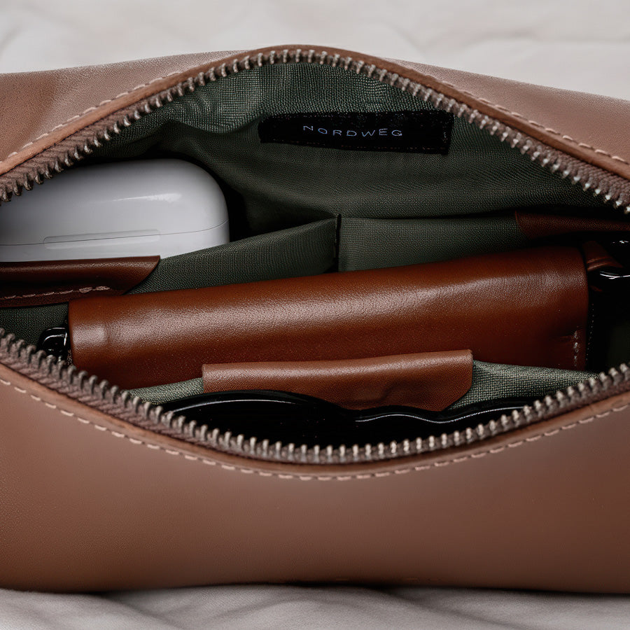 Interior da Sling Bag Pulse NW112 Nordweg, com divisórias funcionais, forro verde e compartimentos para acessórios como fones, carteira e óculos.