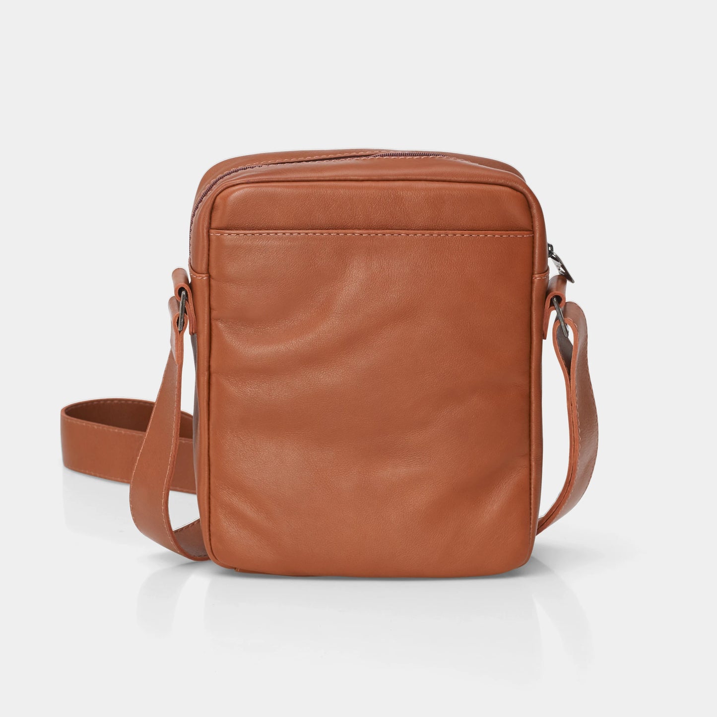 Vista traseira em ângulo da Bolsa de couro para iPad Nômade NW091A na cor caramelo, mostrando o bolso posterior aberto e a alça transversal de couro